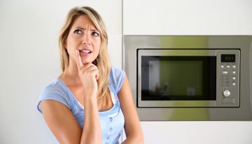 Portrait of woman by microwave oven